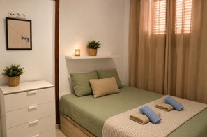 Ein Schlafzimmer mit Bett, Nachttischen, einem an der Wand befestigten Regal mit Pflanzen und einem gerahmten Bild.