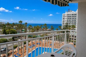 Ein Balkon mit Blick auf einen Swimmingpool, Palmen und ein Hotelgebäude.