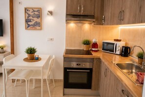 Eine kleine Küche mit Mikrowelle, Kaffeemaschine und integriertem Backofen.