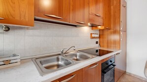 A modern kitchen with wooden cabinets, stainless steel sinks, and a built-in oven. - Apartment 'La Casa Di Giorgia' with Wi-Fi and Air Conditioning (Chioggia)