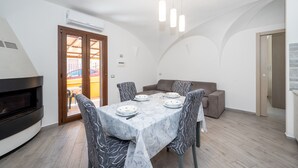 Un coin repas avec une table dressée pour quatre personnes, un canapé et une cheminée.
