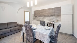 Une cuisine moderne avec un coin repas, un canapé et une table dressée pour quatre personnes.