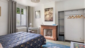 Un dormitorio con cama, escritorio, chimenea y armario.