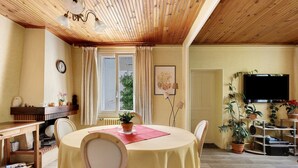 Un comedor con una mesa redonda, sillas, un reloj, una chimenea y un televisor.
