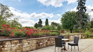 Un patio al aire libre con paredes de piedra, una mesa y dos sillas.