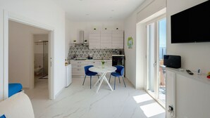 Une cuisine moderne avec un coin repas, un téléviseur fixé au mur et une vue par la fenêtre.