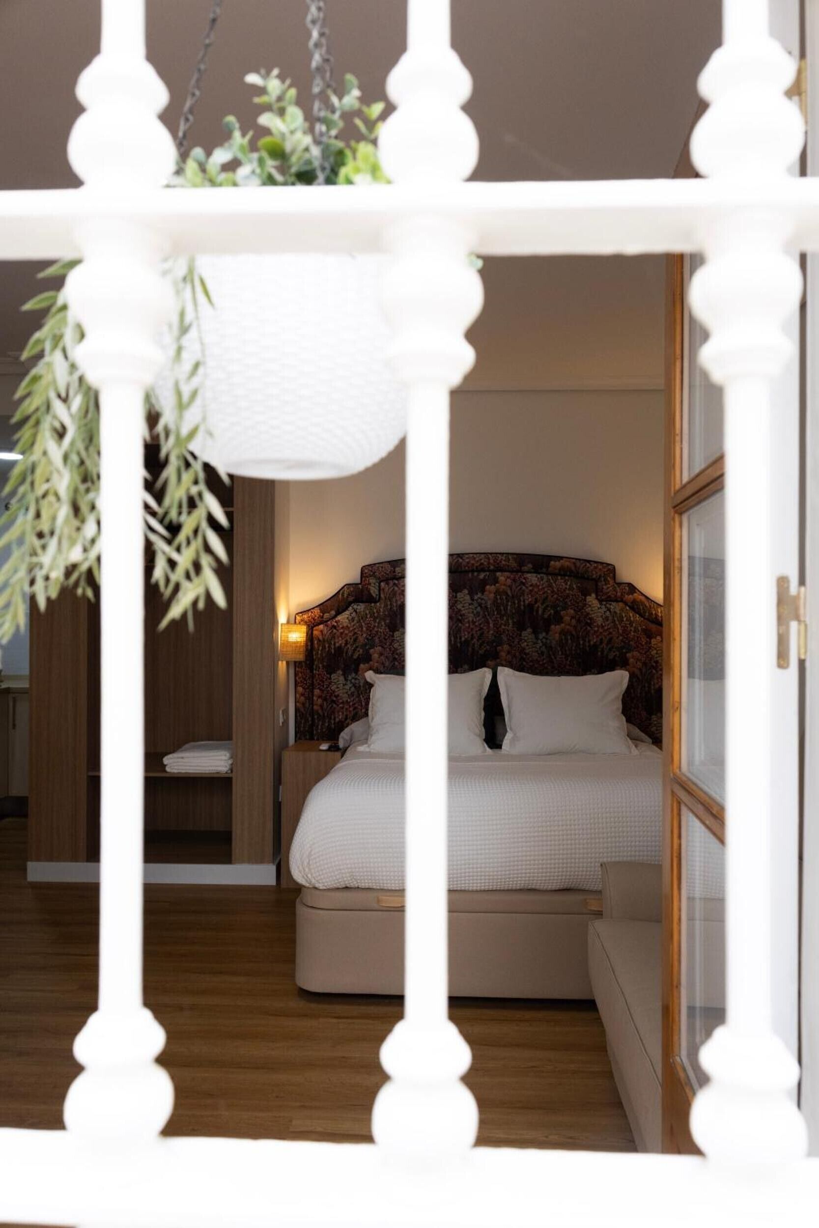 Ein Schlafzimmer mit einem Bett, Nachttischen, einer hängenden Pflanze und Holzboden.
