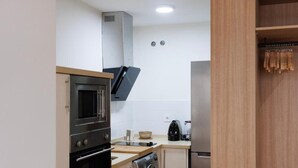Une cuisine compacte équipée d’un four à micro-ondes, d’un four traditionnel, d’un lave-linge et d’un réfrigérateur.