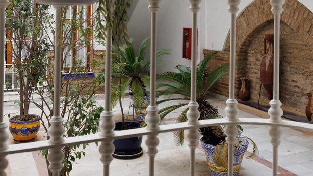 Un atrium à plusieurs niveaux, doté d’un escalier central, de plantes en pot et d’un plafond décoratif.