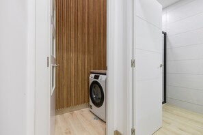 Un lavadero con lavadora, pared de paneles de madera y suelo de baldosas.