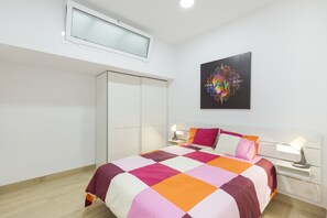 Un dormitorio con cama, lámparas de noche, armario, luz de techo y una obra de arte en la pared.