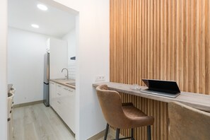 Une cuisine moderne avec des armoires blanches, un réfrigérateur en acier inoxydable et un mur d’accent en bois.