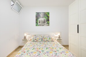 Une chambre à coucher avec un lit, un tableau représentant un Bouddha accroché au mur et des lampes de chevet.