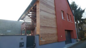 A building with a red facade, a wooden slatted section, and a small window. - Holiday Home 'La Grange De Mediovilla' with Terrace, Private Garden & Wi-Fi (Wingersheim les Quatre Bans)