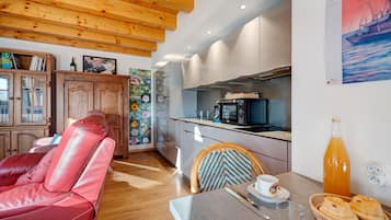 Una cocina moderna con horno empotrado, una mesa de comedor con sillas y un sofá de cuero rojo en la zona de estar.