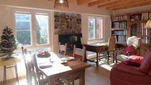 A cozy living room with a wooden ceiling, a fireplace, a bookshelf, and a Christmas tree. - Holiday Home 'La Grange De Mediovilla' with Terrace, Private Garden & Wi-Fi (Wingersheim les Quatre Bans)