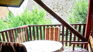 A wooden deck with a round table and two chairs, surrounded by a wooden railing. - Holiday Home 'La Grange De Mediovilla' with Terrace, Private Garden & Wi-Fi (Wingersheim les Quatre Bans)