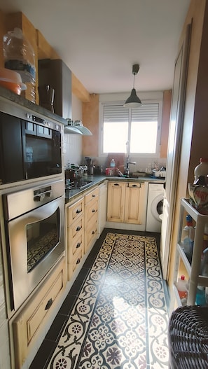 Una cocina equipada con microondas, horno, lavaplatos y lavadora.