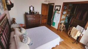 Un dormitorio con cama, cómoda, espejo, armario y una silla.