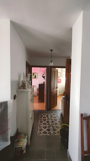 Un pasillo con alfombra estampada, un armario blanco, una puerta de madera y un ventilador de techo.