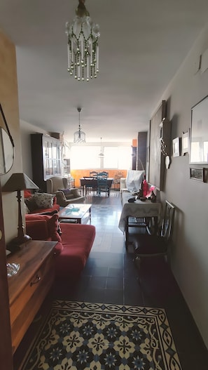 Una sala de estar con una araña, un comedor y un tapete estampado.