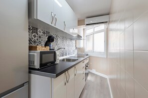 Een moderne keuken met een magnetron, spoelbak en een decoratieve spatwand.