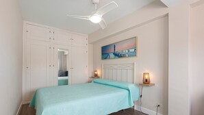 Une chambre à coucher avec un lit, un ventilateur de plafond, un tableau et des lampes de chevet.