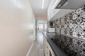 A kitchen with white and black patterned tiles, a stainless steel sink, and a microwave. - Apartment 'Málaga Beach, Costa del Sol' with Mountain Views, Wi-Fi & Air Conditioning (Málaga)