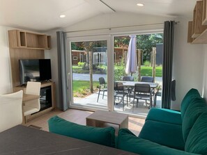 A modern living room with a TV, seating, and a sliding glass door to an outdoor patio. - Holiday Home in Kaatsheuvel With Terrace (Kaatsheuvel)