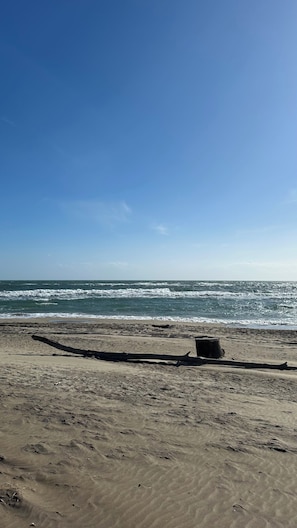 Een zandstrand met een heldere lucht en golven.