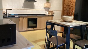 Una cocina moderna con horno empotrado, campana extractora negra y un comedor con mesa y sillas.