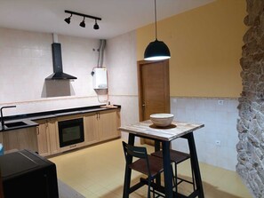 A compact kitchen with a stove, sink, and a small dining table with a bowl.
