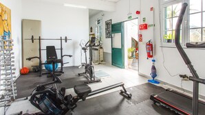 Une salle de sport équipée de matériel d’exercice, d’un tapis de course et d’un panier de basket.