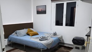 Une chambre à coucher avec un lit, une fenêtre, un tableau au mur et une porte.