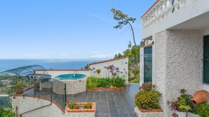 Une terrasse sur le toit avec une piscine, des plantes en pot et une vue sur la mer.