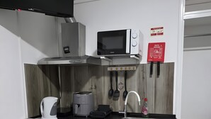 Une petite cuisine équipée d’un four à micro-ondes, d’un grille-pain, d’une bouilloire et d’un évier.