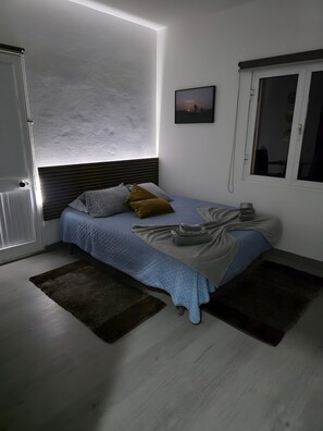 A bedroom with a bed, a bedside table, a window, and a door. - Classic Panoramic View Ocean Apartment with Shared Pool, Garden and Wi-Fi (Gaula)