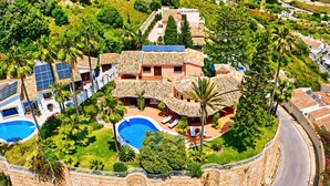 Un gran complejo turístico con múltiples piscinas, un edificio central con techo curvo y abundante vegetación circundante.