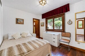 Ein Schlafzimmer mit Bett, Schreibtisch, Stuhl, einem Fenster mit Blick und einer Uhr an der Wand.