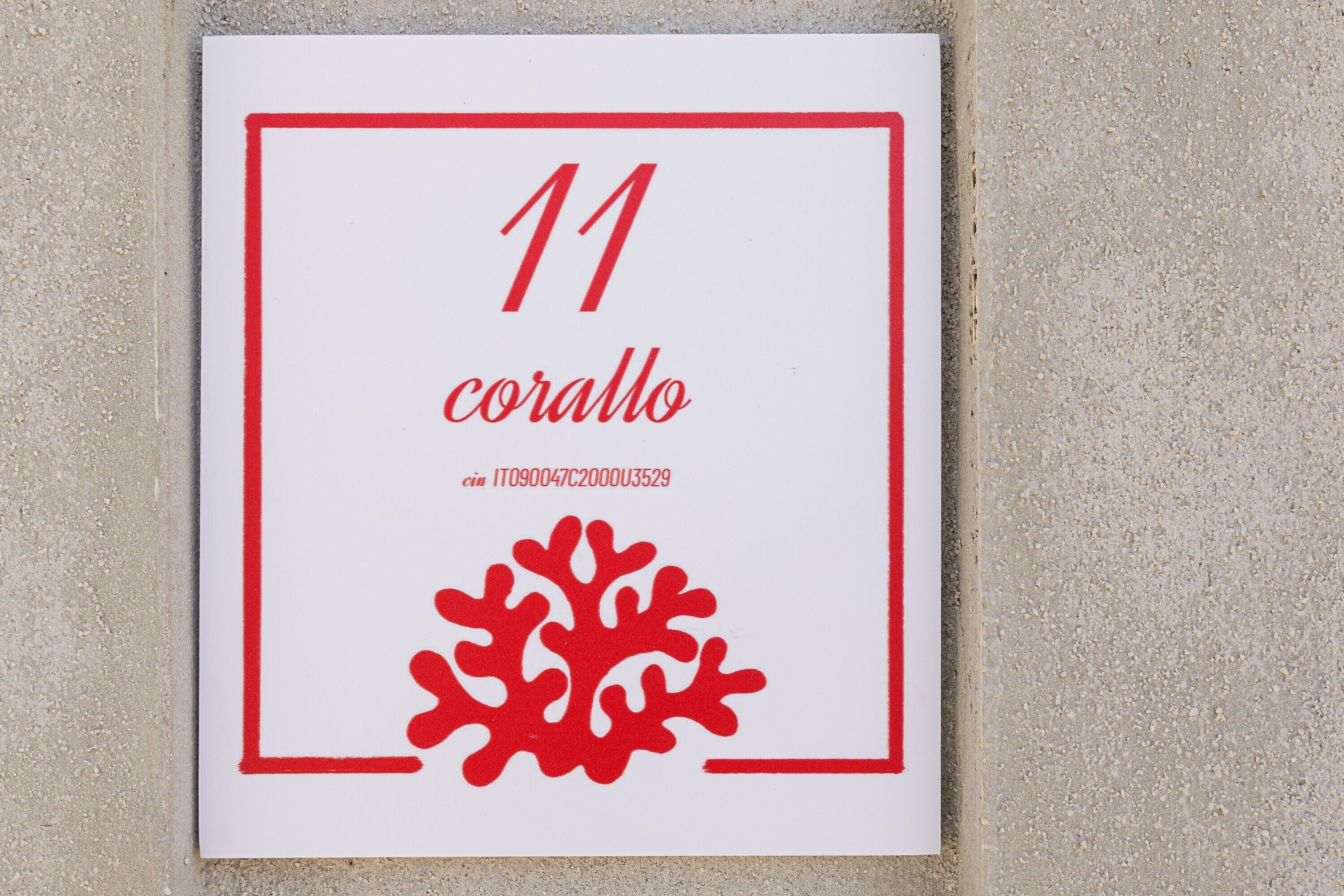 A framed sign with the number 11 and the word 'corallo' in red, along with a red coral-like design.
