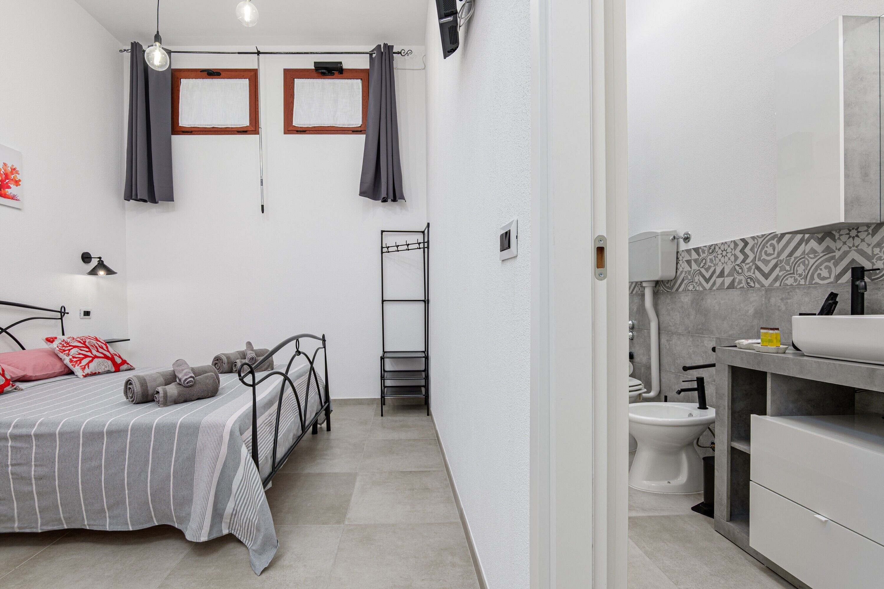 Une chambre à coucher avec un lit, une table de chevet, une lampe et une fenêtre avec des rideaux.