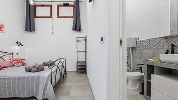 Une chambre à coucher avec un lit, une table de chevet, une lampe et une fenêtre avec des rideaux.