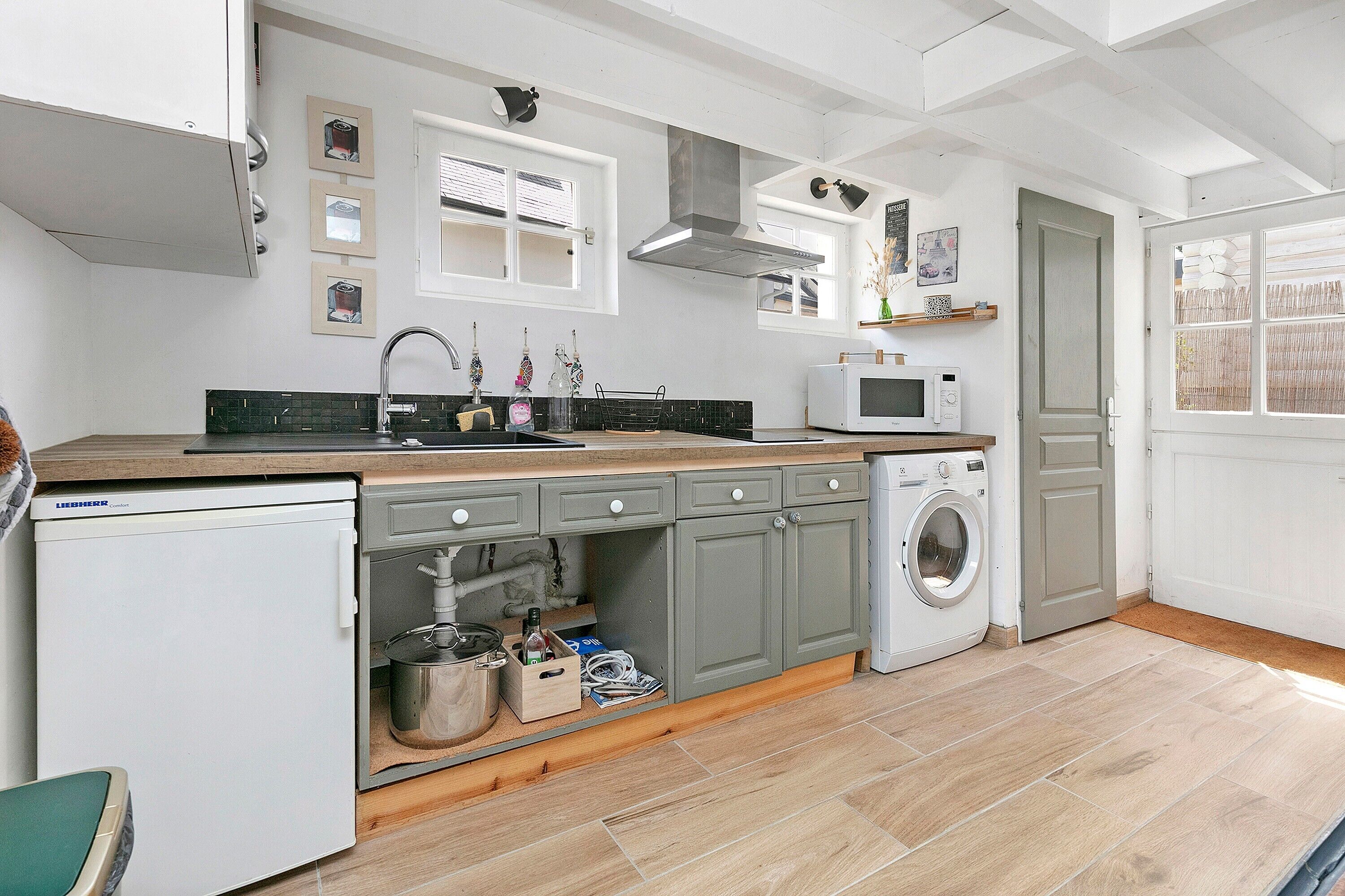 A compact kitchen with a sink, microwave, and washing machine.