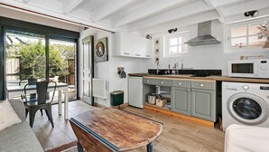 Een moderne keuken met een eethoek, grote ramen en een wasmachine.