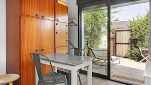Een eetruimte met een tafel, stoelen, een houten kast en een schuifdeur naar een buitenruimte.