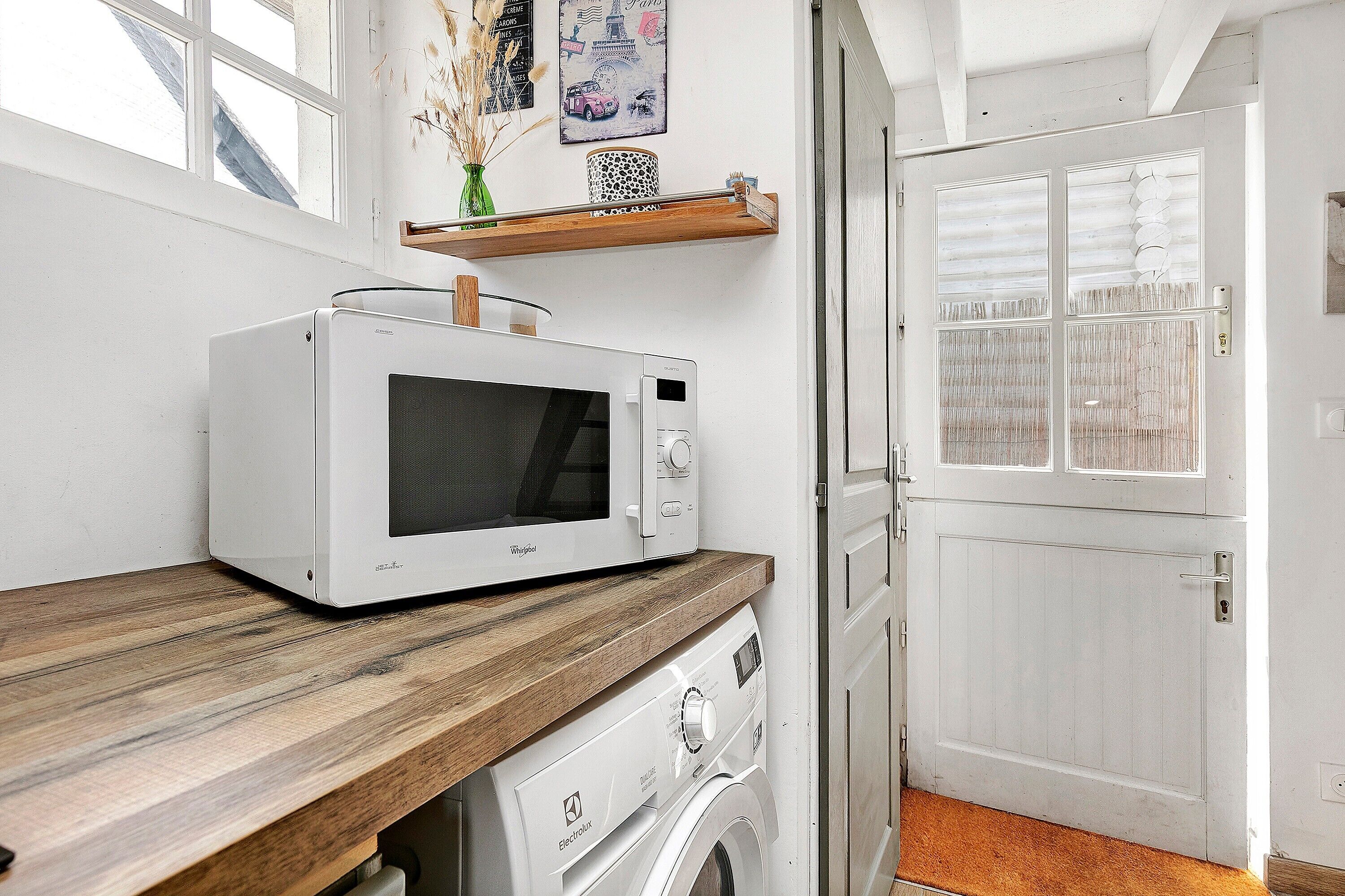 Une cuisine équipée d’un four à micro-ondes, d’un plan de travail en bois et d’un lave-linge.