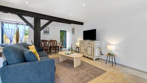 Un salon comprenant un canapé, une table basse, un téléviseur et un coin repas avec des chaises.