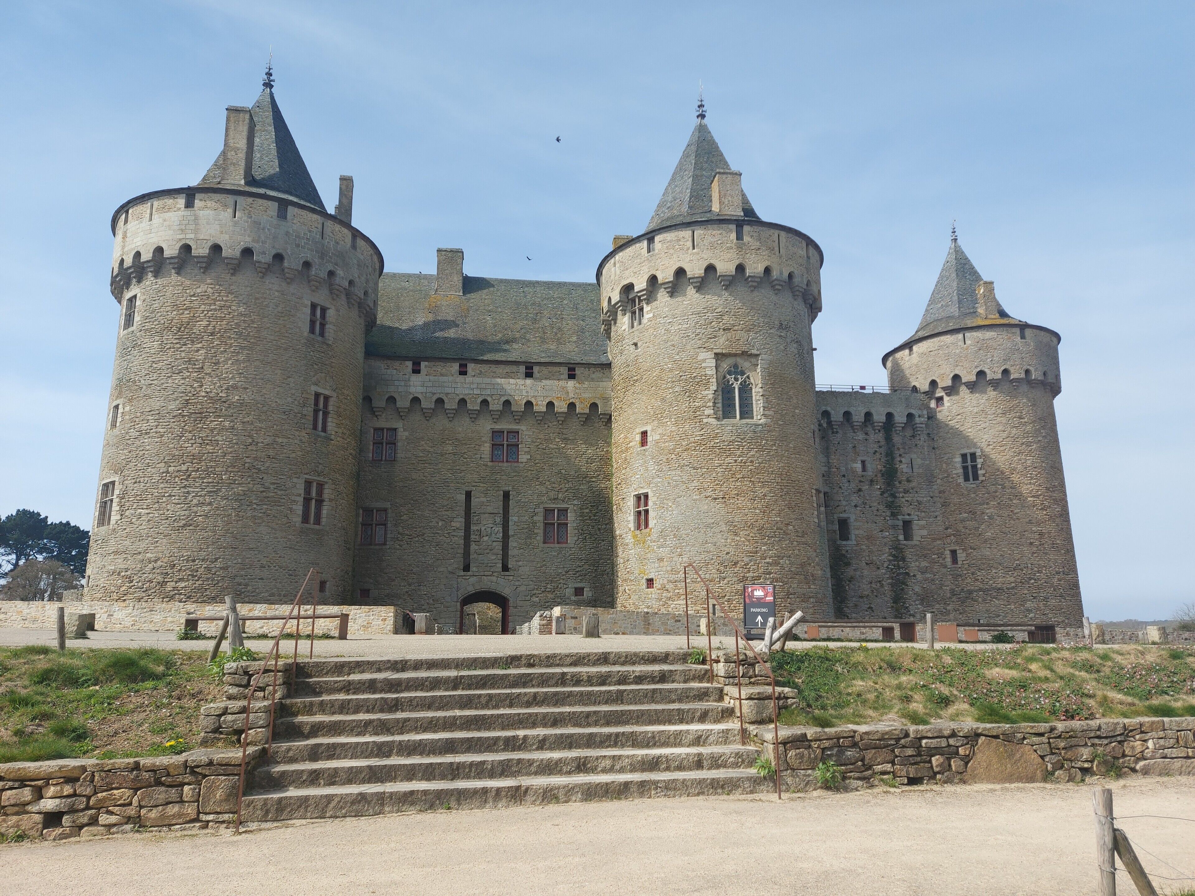 A castle with multiple towers, a central entrance, and stone steps leading up to the entrance.
