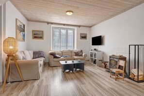 Ein Wohnzimmer mit Sofa, Couchtisch, Lampe, Kamin und Fernseher.