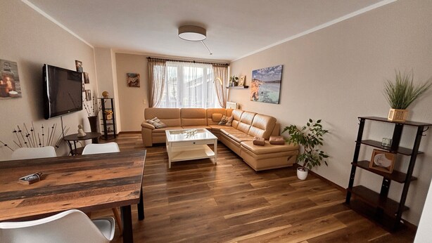 Ein Wohnzimmer mit einer Couch, einem Couchtisch, einem Fernseher und einem Essbereich mit Stühlen und einem Tisch.
